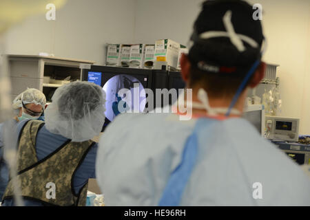 Les cadres supérieurs de l'US Air Force aérienne expéditionnaire Freddy Toruno, 455 e Escadron de soutien médical Technologue en imagerie diagnostique, points au point d'une fracture sur une radiographie au Major Ryan Églefin, orthopédiste, lors d'une chirurgie sur un patient dans une salle d'opération de l'hôpital interarmées de théâtre Craig, l'air de Bagram, en Afghanistan, le 5 août 2014. Le personnel médical de CJTH et 159e Brigade d'aviation de combat, 'USTOFF, administré des soins d'urgence aux victimes impliquées dans l'événement un grand nombre de blessés. Églefin est déployée par le Centre pour le soutien des traumatismes et des compétences de l'état de préparation à Cincinnati, Ohio. M Banque D'Images