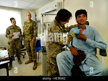 Principaux Jamie Swartz, deuxième à partir de la droite, examine un patient's stitches et incision pendant un rendez-vous de suivi dans l'hôpital humanitaire coréen sur l'air de Bagram, en Afghanistan, le 30 juillet 2013. Swartz, qui est un oto-rhino-laryngologiste, ou d'oreille, nez et gorge chirurgien affecté à la 455 e Expeditionary Medical Group, elle a récemment retiré une tumeur de la gorge du patient. Elle travaille dans l'hôpital interarmées de théâtre Craig ENT Clinic avec son adjoint Le sergent-chef. Robyn Wilcox et chirurgien buccal, l'Armée de terre Le Lieutenant-colonel David Thompson. Le s.. Stephenie Wade) Banque D'Images