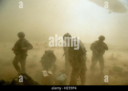 Les membres de l'ARMÉE AMÉRICAINE, 3ème zone, la police frontalière afghane, les forces de sécurité ont délibéré Équipe, se protéger de la poussière et des roches soufflé par UH-60 Black Hawk décoller derrière eux. L'équipe a volé à un avant-poste de la police frontalière afghane à distance dans le sud de l'Afghanistan pour rencontrer les habitants et d'une enquête nouvelle zone de dépôt qui sera utilisé pour réapprovisionner les troupes au sol à l'avant-poste. Banque D'Images