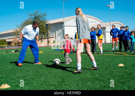 131005-F-WU507-032 : Trois ans Carlsness Elie, fils de Tech. Le Sgt. Tim Carlsness, 366e Escadron de soutien aux opérations, dribble un ballon entre un Boise State University mesdames joueur de football et Ed Moore Broncos, entraîneur adjoint à Mountain Home Air Force Base, Colorado, le 5 octobre 2013. Les Broncos ont visité la base pour montrer l'appréciation pour les militaires, entendu quelques expériences de combat de la vie réelle et l'hôte d'une clinique gratuite pour les membres de la famille. Le sergent-chef. Kevin Wallace/) Banque D'Images