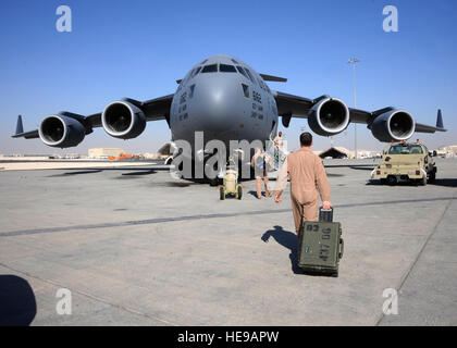 C-17 Globemaster III, les membres de l'équipage à pied vers leurs appareils avec de l'équipement dans la main avant une mission à la 379e escadre expéditionnaire aérienne en Asie du Sud-Ouest, 13 octobre 2013. Le Globemaster III est capable de diffusion stratégique rapide de troupes et tous les types de chargement de bases principales ou directement aux bases avancées dans le déploiement. Les équipages de C-17 affecté au 816th Escadron de transport aérien expéditionnaire sont déployés à partir d'une base commune Charleston, S.C. Senior Airman Bahja J. Jones) Banque D'Images