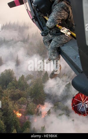 Le Sgt. Chris Boni, chef d'équipage de la Garde nationale de Californie, 1-140ème bataillon de l'Aviation (Air Assault) sur la base de formation conjointe de Los Alamitos (JFTB), les rejets de l'eau sur la tête arrosant le rim fire ci-dessous près de Yosemite National Park. La Rim Fire est maintenant la 14e plus grande forêt à l'histoire de la Californie. L'UH-60 Black Hawk équipages se battent contre la jante de forêt à l'appui de Bureau du Service des forêts des États-Unis et Cal feu.(U.S. Le sergent-chef de la Californie. Julie Avey/ libéré) Banque D'Images