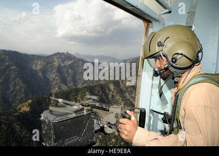 L'Aviateur de l'armée de l'air afghane Abdul Ghani, chef d'équipe, mans son M240 machine gun qu'il examine les environs d'éventuels insurgés lors d'une mission de ravitaillement de combat en barge Matal dans le nord de la vallée de la Kunar, Afghanistan, le 10 octobre 2011. Les forces afghanes et américaines ont volé deux hélicoptères Mi-17 AAF à Barge Matal et livré 3 200 kilogrammes de dollars de fournitures de soldats de l'Armée nationale afghane. Banque D'Images