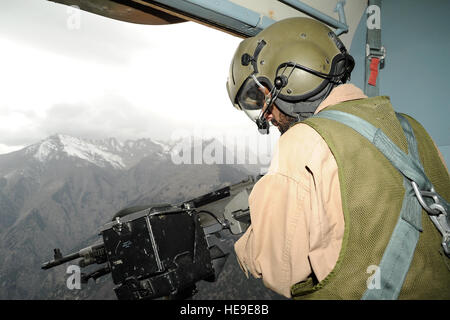 L'Aviateur de l'armée de l'air afghane Abdul Ghani, chef d'équipe, mans son M240 machine gun qu'il examine les environs d'éventuels insurgés lors d'une mission de ravitaillement de combat en barge Matal dans le nord de la vallée de la Kunar, Afghanistan, le 10 octobre 2011. Les forces afghanes et américaines ont volé deux hélicoptères Mi-17 AAF à Barge Matal et livré 3 200 kilogrammes de dollars de fournitures de soldats de l'Armée nationale afghane. Banque D'Images