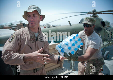 U.S. Air Force Le Capitaine Adam Ackerman, MI-17 conseiller pilote, 441e Escadron expéditionnaire de la comité consultatif, passe un pack de bouteilles d'eau à l'Adjudant-chef 2 Marvin Holmes, 3e de la police des frontières afghanes Zone G-4 ingénierie mentor principal, 504e Brigade de surveillance du champ de bataille, le 5 septembre, lors d'une mission de ravitaillement de subsistance, à l'Escadre aérienne de Kandahar, l'aérodrome de Kandahar, Afghanistan. Pilote américain et les soldats, aviateurs et afghans ont travaillé ensemble pour fournir de l'eau et 137 cas à un repas Halall 5e Kandak ABP check point, Shorabak district. Ackerman est un Palm Beach Gardens, en Floride, les autochtones déployés à partir du 90t Banque D'Images