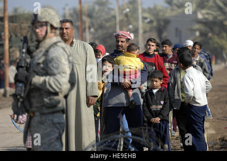 Les résidents d'Hasan annonce Daryush, l'Iraq, la ligne jusqu'à l'extérieur de l'école primaire Falahat tandis qu'un soldat de l'Armée américaine du 2e Escadron, 14e Régiment de cavalerie, 2nd Stryker Brigade Combat Team, 25e Division d'infanterie, fournit la sécurité lors d'un effort médical le 25 janvier 2008. Banque D'Images