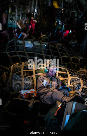 Le s.. Kacie Adsit détend tout en remplissant une grille de mots croisés au cours d'un vol le 20 juillet 2014, dans le sud-ouest de l'Asie. Adsit est un Hercules C-130 de l'arrimeur 737th Escadron de transport aérien expéditionnaire. Les arrimeurs s'assurer que tous les membres du personnel et du fret transportés sécurisés pour l'avion de voler en toute sécurité. Adsit est déployée ici de la 910th Airlift Wing, Youngstown, Ohio Air Station de réserve, à l'appui de l'opération Enduring Freedom. Le s.. Jeremy Bowcock) Banque D'Images