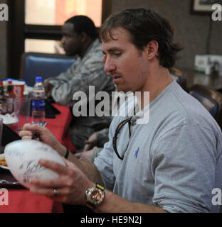 Drew Brees, le quart-arrière de la Nouvelle Orleans Saints et joueur le plus utile du Super Bowl, des autographes a football pour l'un de ses fans pendant le déjeuner dans la salle à manger du Sultan's Inn Mercredi, 24 mars 2010 à la base aérienne d'Incirlik, en Turquie. Brees, ancien secondeur NFL Donnie Edwards et Saints tight end Billy Miller Incirlik visité dans le cadre d'une tournée USO pour rencontrer et saluer les membres du service des États-Unis. Ashley Wood Senior Airman Banque D'Images