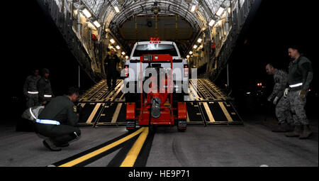 Aviateurs du 28 e Escadron de préparation logistique un guide de camion à quatre roues motrices et la pompe à eau sur un C-17 Globemaster de Ellsworth Air Force Base, S.D., Novembre 2, 2012. La 28e Bomb Wing est un de plusieurs ailes à l'appui des efforts de secours de l'Ouragan Sandy, l'envoi de plusieurs aviateurs du 28e Escadron de génie civil de la région de New York pour effectuer la dépose de l'eau. Navigant de première classe Anania Tekurio) Banque D'Images