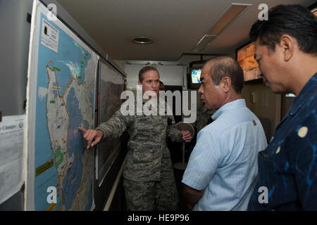 Le Lieutenant-colonel de l'US Air Force Sarah Babbitt, 18e Escadron des Forces de sécurité, explique un commandant de la carte afin d'Hajime Shinzato, chef du poste de police d'Okinawa et Namizato Kazumune, Okinawa de police étrangères, chercheur principal de cas au cours de l'échange d'officiers d'application de la loi constitutive, le 22 octobre 2015, sur Kadena Air Base, au Japon. La carte affiche où nos forces militaires ont autorité sur Okinawa. Navigant de première classe Lynette M. Rolen) Banque D'Images