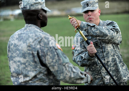 GUANTANAMO BAY, Cuba - l'Armée de terre Le capitaine Nick François (à gauche), commandant de la 193e Compagnie de Police Militaire, passe par les sous-officiers de l'unité d'Épée nouveau MP 193e 1ère compagnie Sgt. Michael Baker, signifiant son acceptation de la responsabilité de l'autorité. 1er Sgt. Baker a assumé la responsabilité d'autorité de la société MP 193e au Groupe de travail conjoint au cours d'une cérémonie à Guantanamo Bulkeley champ, le 4 juin 2010. La 193ème Compagnie MP est responsable d'une partie de la garde de la foi à Guantanamo. Guantanamo la foi mène sûr, humain, juridique et transparent le soin et la garde des détenus, y compris Banque D'Images