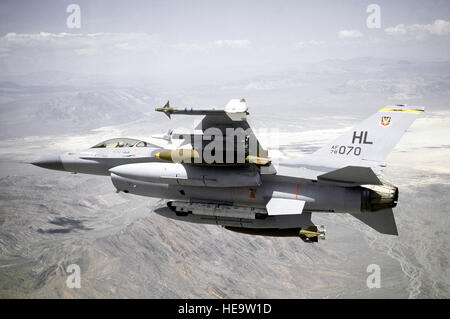 D'un avion d'une vue arrière gauche F-16 Fighting Falcon d'avion vers la droite sur une plage. Un seul but-9L Sidewinder, un seul but, un Sidewinder-9J-2 000 lb Mark 84 bombe et un réservoir de carburant auxiliaire sont sur chaque aile. L'ALQ-119 des contre-mesures électroniques pod est monté sur l'axe central. L'aéronef est affecté au 4e Escadron d'appui tactique, 388e Escadre de chasse tactique. Banque D'Images