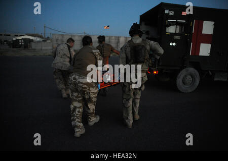 Le s.. William Lawson (à droite), pararescueman avec le 129e Escadron de sauvetage expéditionnaire, aide les forces de la coalition portent un soldat de l'armée nationale afghane blessés à l'ambulance, l'aérodrome de Kandahar, Afghanistan. Banque D'Images