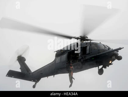 Une 320e Escadron tactique spéciale pararescueman descend un membre de l'équipe de l'or hors de l'eau en un à base de Kadena HH-60 du 33e Escadron de sauvetage au cours de l'or Thunder 2.0 s'est déroulée au Camp le 24 juillet 2015, Hansen. Le scénario de l'exercice s'est terminé par un assainissement et l'évacuation de l'emplacement avancé d'opérations par l'eau par les aéronefs à voilure tournante. Thunder Gold 2.0 est une aide humanitaire de secours en cas de catastrophe/exercice scénario mis ensemble pour former le personnel de soutien de mission de combat dans la terre et l'eau la navigation, l'établissement d'un centre d'opérations tactiques spéciales et une plateforme logistique le long de w Banque D'Images