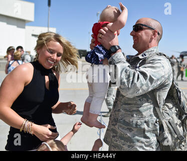 140523-F-WU507-628 : un 726e Escadron de l'air capitaine détient sa jeune fille comme sa femme et sa fille, d'autres regarder sur immédiatement après son retour de déploiement en Afghanistan 23 mai 2014. 'Hardrock' aviateurs fourni critiques temps de commandement et de contrôle de gestion de la bataille à l'aide de capteurs et de communication situé à l'ensemble de l'Afghanistan. Le sergent-chef. Kevin Wallace/) Banque D'Images