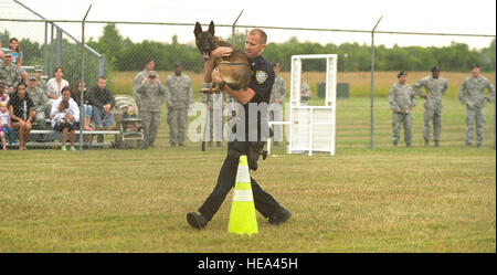 Titus Clouse, un agent de la Police de Minot, porte son enfant de 2 ans K-9, Piko, lors d'un des nombreux obstacles dans le K-9 concours tenu au 5e Escadron des Forces de sécurité sur les chenils chien Minot Air Force Base, N.D., 14 août 2013. Le Dakota du Nord 2013 Agent de la paix Association K-9 Essais Police présenté neuf équipes canines de partout dans l'état, militaires et civils. Kristoffer Navigant de première classe Kaubisch) Banque D'Images