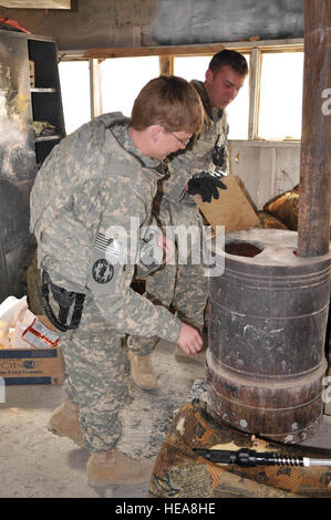 La province de Paktia, Afghanistan - Armée américaine Sgt. Crista Tucker et la CPS. Brandon la démarque, tous deux de la Compagnie de la Police militaire de la 410th hors de Fort Hood, au Texas, se réchauffer par une cuisinière dans leur garde shack cuisinière tandis que sur leur service de garde à la base d'opérations avancée Éclair, dans l'Est de l'Afghanistan. U.S. Air Force capitaine principal Sgt. Jessica D'Aurizio, 203e Corps canadien, Affaires publiques de l'Armée nationale afghane Advisory Team) Banque D'Images