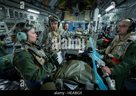 De gauche à droite, le capitaine de l'US Air Force Danielle Cooper, infirmière de vol, 43e Escadron d'évacuation aéromédicale, Pape Army Airfield, N.C., entretiens avec les membres de l'équipe transport soins critiques de l'US Air Force, le Lieutenant-colonel Alan Guhlke, anesthésiologiste, et le capitaine Daniel Bevington, infirmière en soins intensifs, à la fois avec 711e Escadre de la performance humaine, Wright-Patterson Air Force Base, Ohio, tandis qu'à bord d'un C-17 Globemaster III à Joint Readiness Training Centre (JRTC), de Fort Polk, en Louisiane, le 18 janvier 2014. Les membres du service au JRTC 14-03 sont éduqués dans la lutte contre les soins aux patients et l'évacuation aéromédicale dans un environnement de combat simulé. Ma Banque D'Images