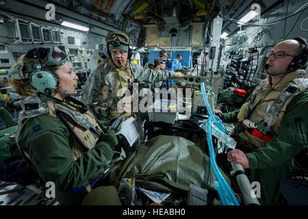 De gauche à droite, le capitaine de l'US Air Force Danielle Cooper, infirmière de vol, 43e Escadron d'évacuation aéromédicale, Pape Army Airfield, N.C., entretiens avec les membres de l'équipe transport soins critiques U.S. Air Force, le Lieutenant-colonel Alan Guhlke infirmier anesthésiste et le capitaine Daniel Bevington, infirmière en soins intensifs, à la fois avec 711e Escadre de la performance humaine, Wright-Patterson Air Force Base, Ohio, tandis qu'à bord d'un C-17 Globemaster III à Joint Readiness Training Centre (JRTC), de Fort Polk, en Louisiane, le 18 janvier 2014. Les membres du service au JRTC 14-03 sont éduqués dans la lutte contre les soins aux patients et l'évacuation aéromédicale dans un environnement de combat simulé. Mas Banque D'Images