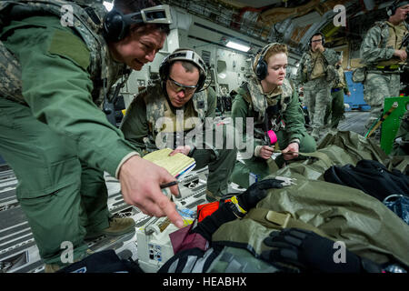 De gauche, tactical critical care - amélioration de l'équipe expéditionnaire (TCCET-E) membre de l'US Air Force, le Capitaine Richard Rogers, infirmière anesthésiste, 86e Groupe médical, Base aérienne de Ramstein, en Allemagne, et le major de l'US Air Force Corey Norton, infirmière de vol, 43e Escadron d'évacuation aéromédicale, Pape Army Airfield, N.C., l'enregistrement des signes vitaux du patient en tant que Senior Airman Nichole Kilinc, compagnon de service aéromédical, également avec la 43e sur un patient simulé sangles tandis qu'en vol à bord d'un C-17 Globemaster III à Joint Readiness Training Centre (JRTC), de Fort Polk, en Louisiane, le 18 janvier 2014. Les membres du service au JRTC 14-03 sont e Banque D'Images