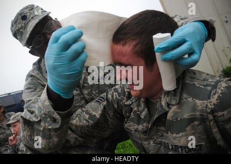 Le lieutenant-colonel Joseph Ouma, 8e Groupe médical, des enveloppements d'un bandage autour de la tête de l'Aviateur Senior Donald Feutres, 8e Escadron de maintenance des aéronefs, lors de l'exercice Beverly minuit 14-2 à Kunsan Air Base, République de Corée, le 15 juillet 2014. L'exercice de l'état de préparation opérationnelle et les capacités de mission évalue assure la meute est dans un état de préparation. Airman Senior Curry Taylor Banque D'Images