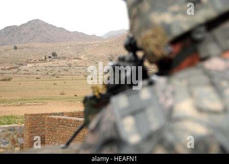 La CPS de l'armée américaine. Lee Peacock de Pensacola, Floride, attribué à l'Équipe de reconstruction provinciale de Kunar, forces de sécurité du 1er escadron, le 221e régiment de cavalerie, la Garde nationale du Nevada à Las Vegas, numérise l'horizon alors que les ingénieurs de l'ERP conduite un contrôle de qualité sur la construction à l'École de Marawara Dag de Lahore, l'Afghanistan, le 14 janvier. Banque D'Images