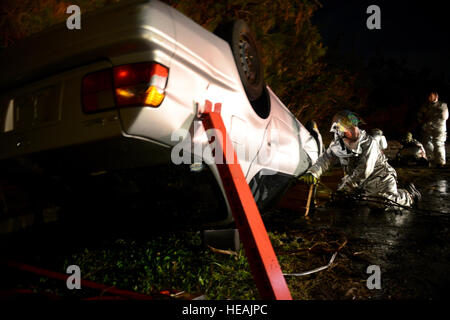 Un pompier de l'US Air Force à partir de la 18e Escadron de génie civil de l'aide de la part d'autres pompiers attend pendant une simulation de sauvetage d'accidents de véhicules automobiles dans le cadre d'une mission axée sur l'exercice Kadena Air Base, le Japon, le 3 décembre 2014. Le MFE est conçu pour former les aviateurs de l'Kadena techniques et procédures pour une gamme de scénarios d'attaques chimiques à des pertes massives. Airman Senior Maeson L. Elleman Banque D'Images