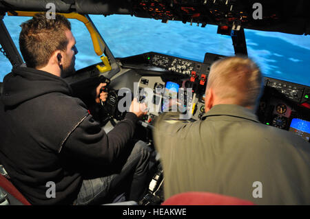 RAF MILDENHALL, Angleterre -- Le Capitaine Joshua Hiam, 100e Escadre de ravitaillement en vol, d'ajuster certains paramètres dans le KC-135 simulateur de vol, comme les arts martiaux mixtes fighter Ryan Badar prend son envol au cours d'une visite à la base le 14 octobre 2010. Badar et deux autres combattants MMA a pris le temps de visiter avec les membres de la 352e et 100e groupe d'opérations spéciales de l'Escadre de ravitaillement en vol alors que j'étais en ville pour un événement. Tech. Le Sgt. Bois Marelise) (publié) Banque D'Images