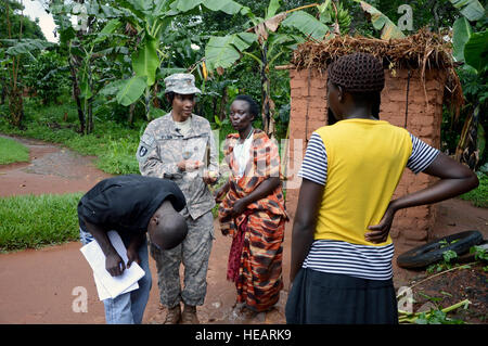 Le Major de l'armée américaine Daisy Wilson, une infirmière de la santé publique avec le 411e Bataillon des affaires civiles, Combined Joint Task Force-Horn of Africa, clé de la santé tire les données d'évaluation de leader communautaire et de la famille comme Nalubwma Vincent vétérinaire ougandais le Dr Douglas Kibuuka, Bombo, résultats records au cours d'une étude de site de dizaines de maisons dans le village reculé de Kakute, site de la dernière discussion Ebola en novembre. La santé humaine et animale de l'équipe de soins de santé fait partie de l'un, deux semaines de point de programme qui renforce l'Ouganda et l'counterbioterrorism et capacités reco Banque D'Images