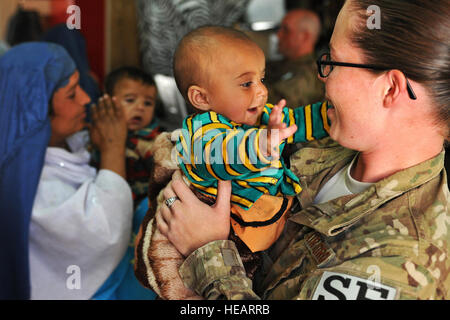 Navigant de première classe Riostasia Johns est titulaire d'un Afghan bébé pendant que sa mère les processus grâce à l'entrée control point médical le 16 avril 2013, à l'aérodrome de Bagram, en Afghanistan. Les aviateurs et les gardes locaux afghans d'assurer la sécurité et la collecte d'information pour identifier et suivre les dossiers de tous les patients entrant. Johns est une entrée contrôleur assigné à la 455 e Escadron des Forces de sécurité de la Force expéditionnaire du Canada. Chris Willis) Senior Airman Banque D'Images