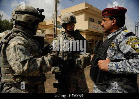 Le capitaine de l'armée américaine Eric Dunkley (centre), Bravo Troop, 4e Escadron, 9e régiment de cavalerie, 2e Brigade, 1e Division de cavalerie, avec son interprète, Steve (à gauche), et le lieutenant-colonel de la police nationale irakienne Mahmoud (droite) de Salah bataillon, police nationale de Mossoul, discuter des procédures pour une mission dans le quartier de Tal Al Ruman de Mosul, Iraq, le 25 mars 2009. Banque D'Images