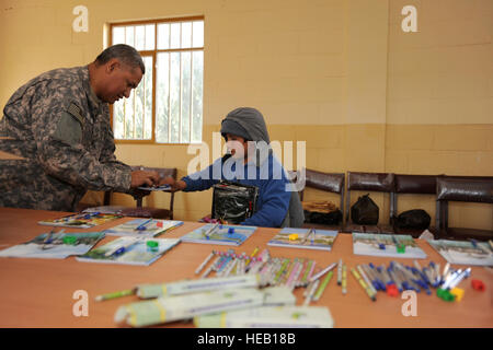 Au cours d'une visite à l'orphelinat de la ville de Farah Farah, Équipe provinciale de reconstruction (EPR) de l'ARMÉE AMÉRICAINE Le Capitaine Ivan Nunez, un membre de l'équipe des affaires civiles de l'EPR, distribue des fournitures scolaires aux enfants, le 23 décembre 2009. Tous les articles donnés notamment des vêtements, des chaussures et des bonbons ont été donnés à l'orphelinat par 10 entrepreneurs afghans locaux. L'EPR a organisé la collecte et la distribution des produits, mais n'a offert aucune aide monétaire. Banque D'Images