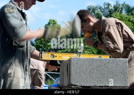 Le sergent de l'US Air Force. Dustin Haycox, 823e Escadron expéditionnaire Cheval Rouge artisan structurel, hors de Hurlburt Field, en Floride, et le sergent du Corps des Marines des États-Unis. Jason Kelleher, ingénieur de combat avec le 271e Escadron de soutien de l'aile Marine, 2e escadre aérienne de la Marine, à partir de Marine Corps Air Station Cherry Point, N.C., bloc pour construire le mur de la chambre de la pompe sur le site du puits mur au Honduras Aguan, Honduras, 24 juillet 2015. La station de pompage est un projet supplémentaire des membres de la formation de nouveaux horizons Honduras 2015 Équipe d'exercice ont été en mesure de travailler après avoir terminé leur projet principal, le nouveau deux-Cla Banque D'Images