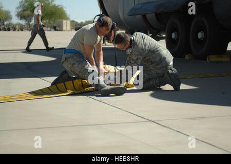 Un membre de la 1re classe Daniel J. Boutwell et Corey B. Sweeny-Morehouse, 755e Escadron de maintenance des aéronefs de la guerre électronique des techniciens, brancher un tuyau de climatisation pour refroidir un EC-130H Compass Call avion à la base aérienne Davis-Monthan Air Force Base, en Arizona le 1 mai 2013. L'aéronef doit maintenir une température fraîche, de sorte que les ordinateurs de l'arrière ne pas surchauffer. Navigant de première classe Betty R. Chevalier/libérés) Banque D'Images