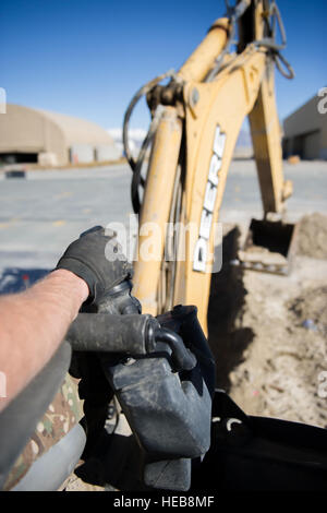 Un technicien en chaussées et en équipement du 455e Escadron expéditionnaire du génie civil exploite une pelleteuse à Bagram Air Field, en Afghanistan, préparant un site pour le ciment pour un projet de construction de structures de maintenance de grande superficie. Banque D'Images