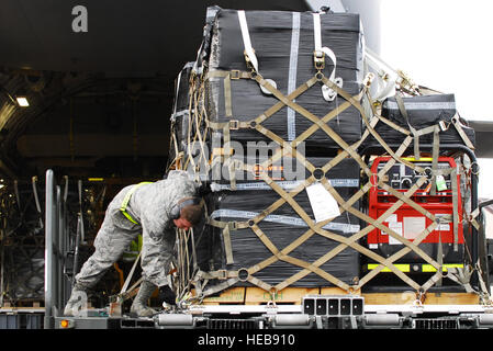 YOKOTA AIR BASE, Japon -- hauts Airman Jack Hunter, 730th Escadron la mobilité de l'air, technicien des services de piste, se resserre sur une palette contenant les pièces pour une pompe à eau ici le 22 mars. La Royal Australian Air Force C-17 Globemaster III livré l'équipement à Yokota avant d'être transportés à Fukushima, au Japon. Le s.. Robin Stanchak) Banque D'Images