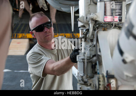 Le sergent-chef. Raymond Sambor, 451e Escadron de préparation logistique expéditionnaire port aérien, attache une chaîne de chargement sur un F/118 Super Hornet à l'aérodrome de Kandahar, Afghanistan, le 18 août 2011. Sambor et plusieurs membres de la 451e antenne SEIE a aidé le port de charge un F/A-18 Super Hornet sur un C-5 Galaxy. C'était la première fois qu'un chasseur à réaction américain a été chargé dans un avion-cargo pour le transport vers les États-Unis. Après des mois de planification et de coordination, les leaders supérieurs à la Naval Air de la Marine et la Force aérienne des Forces canadiennes a approuvé un Air Mobility Command Banque D'Images