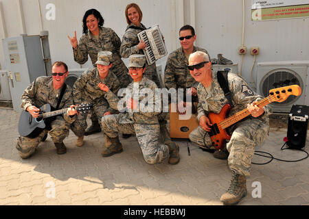 Les cadres supérieurs de l'US Air Force Airmen Desirae Echeverri, 380e Groupe médical expéditionnaire technologue en imagerie diagnostique, déployés à partir de Lackland Air Force Base, Texas, et Jeraka Quenga, 380e de l'Aerospace Medical EMDG, technicien des services déployés à partir de la Nellis Air Force Base, Nevada, posent avec l'US Air Forces Central Bande 'force' Total au cours d'une 'performance' à la traîne dans un endroit inconnu, en Asie du Sud-Ouest, le 26 février 2013. Le groupe a joué dans plus de 10 centres de travail pendant leur dernière tournée d'une semaine avant son redéploiement à Base Aérienne Robins, Ga Tech. Le Sgt. Christina M. Styer Banque D'Images