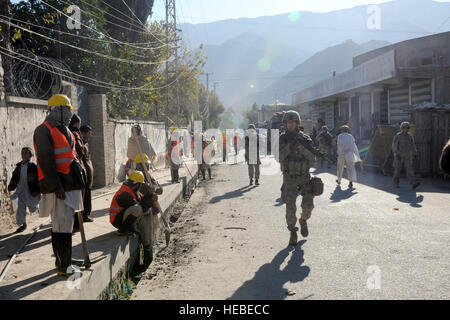 Les travailleurs locaux nettoyer les rues au centre-ville d'Asadabad regarder une Team-Kunar de reconstruction provinciale à une dernière patrouille l'assurance qualité et le contrôle de qualité sur une nouvelle route de 4 kilomètres à travers la capitale provinciale avant une cérémonie, le 13 décembre 2009. Les ingénieurs n'Team-Kunar de reconstruction provinciale la vérifier pour s'assurer que l'entreprise de construction de Kunar, fait un bon travail pour la construction de la route. Le projet a pris près d'un an et d'environ 1 millions de dollars pour terminer. L'espoir pour la nouvelle route est il continuera de stimuler le développement économique et la croissance de l'emploi dans la ville. Plus de 50 provi Banque D'Images