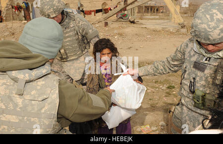 Les membres du service des États-Unis donnent une fille afghane un sac de jouets dans un camp de réfugiés au cours d'une mission de relations communautaires bénévoles dans Kaboul, Afghanistan, le 18 décembre 2009. Le programme MVR, facilité par le Camp Eggers, les aumôniers militaires et civils utilise des bénévoles pour distribuer des marchandises données par personne et d'organismes de charité aux États-Unis et à l'étranger. Magnétoscope les bénévoles d'interagir avec les ressortissants locaux à divers endroits dans Kaboul, dont des écoles, des orphelinats, des centres médicaux et des camps de personnes déplacées, l'amélioration de la vie de tout le monde. Banque D'Images