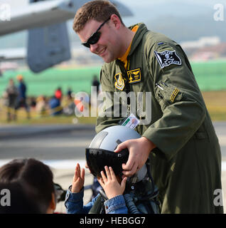 Un officier de l'armée de l'air américaine aide un garçon coréen local à essayer un casque de vol à l'exposition internationale de l'aérospatiale et de la défense de Séoul de 2015 à l'aéroport de Séoul, République de Corée, Oct. 24. L'exposition permet aux membres américains de service d'interagir avec le public tout en présentant des avions et des équipements de défense. Banque D'Images