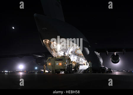 Le sergent-chef de l'US Air Force. John Sadorf, un C-17 Globemaster III loadmaster déployés à partir du 313e Escadron de transport aérien, sur le terrain, Washington, McChord guide le conducteur d'un camion de Mobilité élargi camion tactique comme il le dos jusqu'à l'appareil dans le cadre d'une mission de redéploiement. L'équipage du C-17 fait équipe avec aviateurs affectés à la 455 e Escadron expéditionnaire port aérien de se délester de six véhicules ambulatoires afghane avant de télécharger deux lourds camions tactiques de Mobilité élargi de l'air à Bagram, en Afghanistan, le 20 juillet 2014. Sadorf est originaire de Puyallup, Washington (É.-U. Air Force photo par le Sgt. Cohen A. Young/Re Banque D'Images