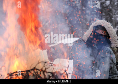 Le capitaine de l'US Air Force Hyon Joo, 962e Airborne Air Control Squadron médecin de Joint Base Elmendorf Richardson, Alaska, utilise un feu clignotant d'améliorer la visibilité d'un signal de fumée Mk-13, 22 février 2013, Eielson Air Force Base, en Alaska. La chaleur de l'incendie pousse le signal de fumée dans l'air plus élevé, augmentant les chances d'être remarqué par les opérations de sauvetage. (U.S. Air Force Photo/Peter Reft Navigant de première classe) Banque D'Images