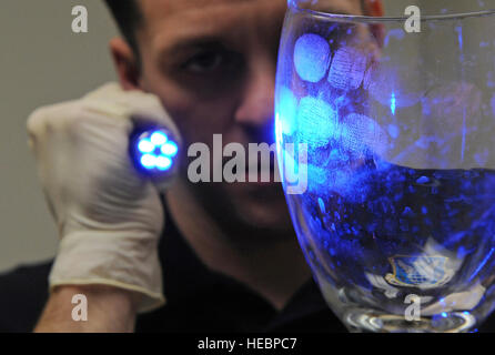 Agent spécial juge Adam, de l'Air Force Office of Special Investigation 219 Détachement, brille la lumière sur un verre de révéler des empreintes digitales en Base aérienne de Barksdale, en Louisiane, 18 janvier. Jugent épousseté la vitre avec une poudre orange qui aide à détecter les agents de doigt à l'uv. (U.S. Air Force photo/Navigant de première classe Mich Anthony) Banque D'Images