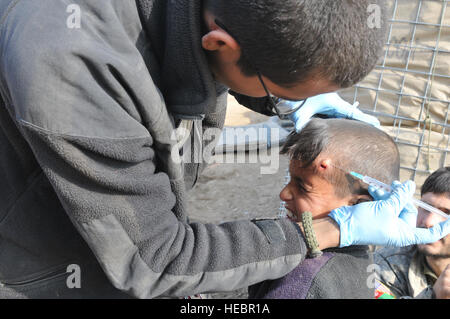 La CPS. Oscar Castro, blanc, du peloton des troupes Bulldog medic, déployés à partir de la 1ère Brigade, 4e Division d'infanterie à Fort Carson, Colorado, anesthésique s'applique à 10 ans Abdul Hagh's Head au poste de combat, Delorean Bala Murghab Baghdis, province, Afghanistan, Janvier 8, 2011. Lorsque le peloton de soldats blancs ne sont pas impliqués dans les activités de cinétique, ils effectuent des opérations de contre-insurrection, les initiatives de développement, et parfois une aide médicale à la population locale. Banque D'Images