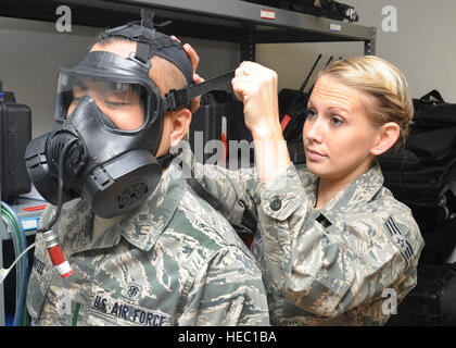 Airman Senior Justeen, Swihart 97e Groupe médical technicien en génie de l'environnement bio, resserre masque à gaz d'un membre de la 1re classe Don Nathaniel, Wentzel 97e Groupe médical bio tech ingénierie environnementale à l'office de l'environnement Bio 10 janvier 2011. Des tests d'adéquation quantitative assurer émis des masques à gaz sont correctement s'adapter aux utilisateurs d'augmenter la protection individuelle lors d'un incident chimique, biologique, radiologique ou une attaque nucléaire. Banque D'Images