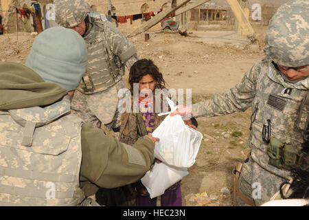 Les membres du Service des États-Unis donnent une fille afghane un sac de jouets dans un camp de réfugiés au cours d'une communauté de bénévoles Relations (Magnétoscope) mission à Kaboul, Afghanistan, le 18 décembre 2009. Le programme MVR, facilité par le Camp Eggers, les aumôniers militaires et civils utilise des bénévoles pour distribuer des marchandises données par personne et d'organismes de charité aux États-Unis et à l'étranger. Magnétoscope les bénévoles d'interagir avec les ressortissants locaux à divers endroits dans Kaboul, dont des écoles, des orphelinats, des centres médicaux et des camps de personnes déplacées, l'amélioration de la vie de tout le monde. (U.S. Des Photo S de l'Armée de l'air Banque D'Images