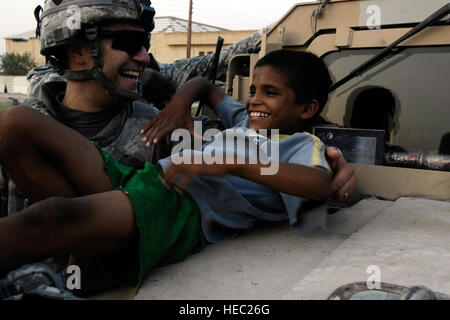 L'ARMÉE AMÉRICAINE Cpt. Vincent Cesaro, originaire de Chicago, Illinois, le confort d'un garçon irakien comme un grand morceau de verre est déposé du fond de son pied lors d'une visite au village de la famille de l'Iraq à Bagdad, l'Iraq, 1 septembre 2008. Cesaro est du Siège Siège Batterie, 1er Bataillon, 320e Régiment d'artillerie, 2e Brigade Combat Team, la 101e Division aéroportée. Banque D'Images