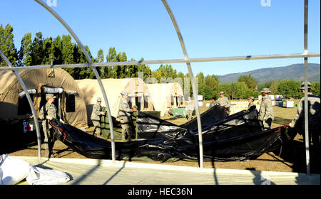 Le personnel de soutien médical expéditionnaire de la Force aérienne et des membres de l'armée chilienne préparent une bâche pour le toit d'un hôpital mobile à Angol, au Chili, le 12 mars 2010, ajoutant une salle d'opération et trois salles de soins à la demande des responsables médicaux locaux. Banque D'Images