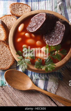 Soupe aux haricots délicieux Fabada Asturiana libre dans un bol en bois vertical Vue de dessus. Banque D'Images